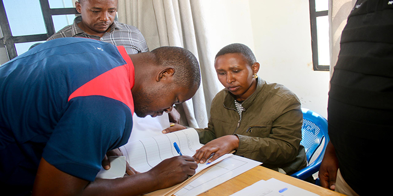 Mkazi wa Nzuguni, Benjamini Elias akisaini katika daftari la fidia wakati wa zoezi la ulipaji fidia kwa wakazi wa Nzuguni jijini Dodoma ambao maeneo yao yamechukuliwa na DUWASA. Agosti 11,202
